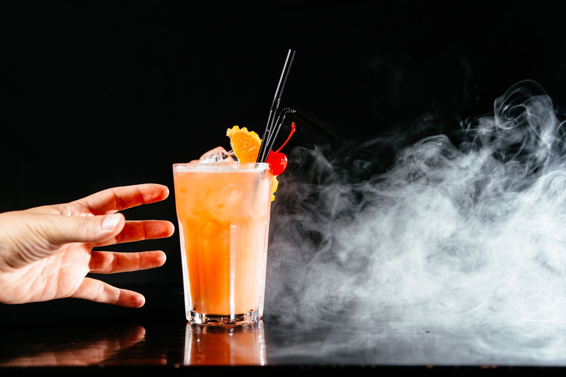 Colorful cocktail on black background. Man taking cocktail drink. Hand grabbing alcoholic drinks.